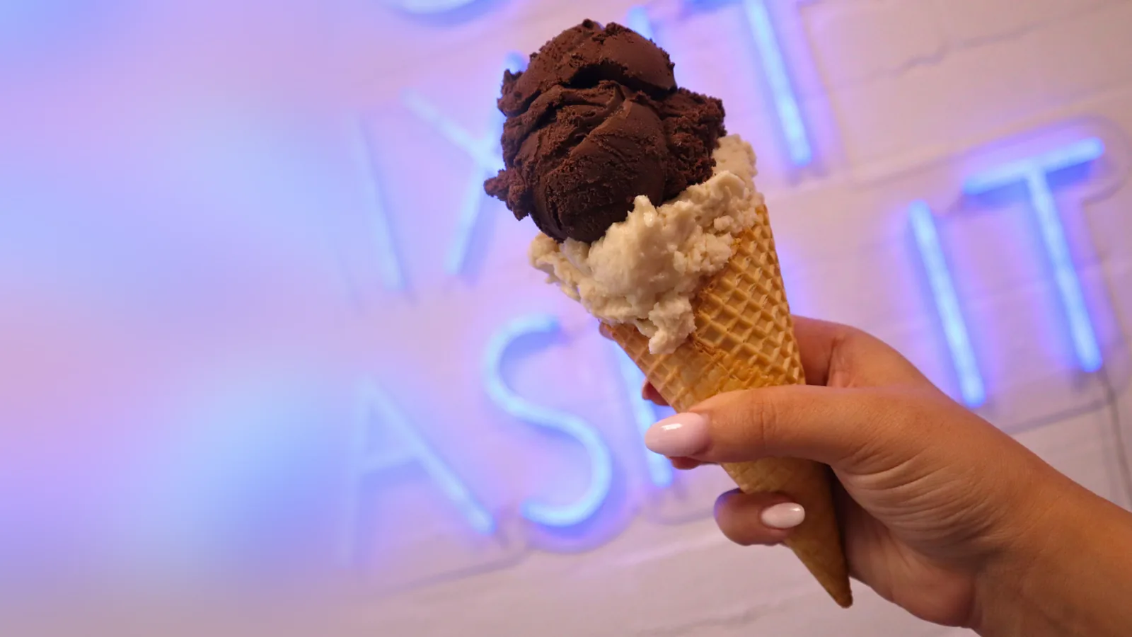 A Cold Rock ice cream cone in front of a neon sign